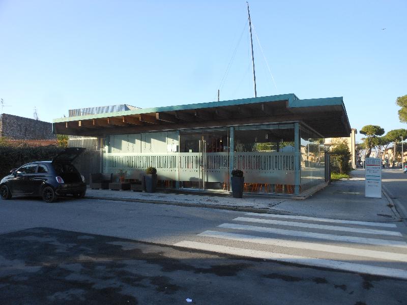 Locale commerciale a destinazione ristorante, libero su tre lati, che si sviluppa su un unico piano fuori terra. Il bene, che si sviluppa su pianta di forma irregolare, è costituito da una porzione in muratura mista ove sono posti il locale cucina ed i servizi annessi, ed una porzione completamente vetrata dove si trova la sala ristorante. Completa la proprietà un piccolo resede esterno posto sul lato sinistro del fabbricato ed un ampio pergolato. Il fondo commerciale è completo di tutti gli impianti (elettrico, idrico, termoelettrico). Identificativi catastali: C.F. del Comune di Viareggio, foglio 27, particella 719, subalterno 1.