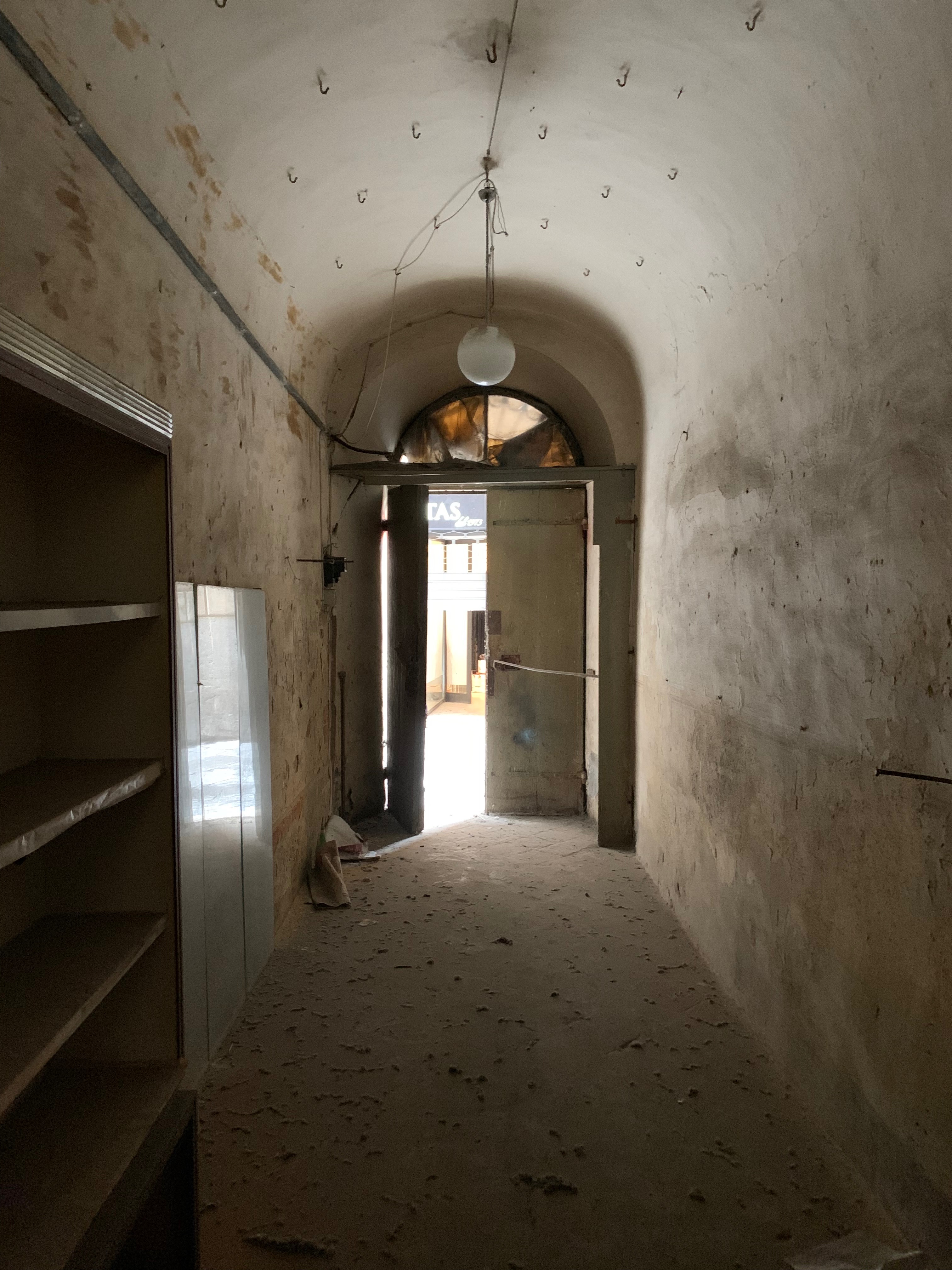 Unità immobiliare a destinazione commerciale situata al piano terra di un edificio di carattere storico-artistico denominato “Palazzo Piccolomini”. La parte più antica, di cui fa parte l'unità immobiliare in esame, è stata costruita su progetto del Rossellino ed era anticamente la dimora della celebre famiglia senese dei Piccolomini. Il fondo commerciale risulta composto da un unico ambiente con forma planimetrica rettangolare, stretta ed allungata, areata da una finestra posizionata sul lato opposto rispetto all’ingresso da via del Porrione. Identificativi catastali: C.F. Comune di Siena foglio 134, particella 13, subalterno 12.