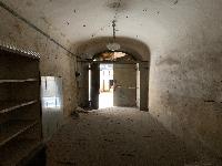 Unità immobiliare a destinazione commerciale situata al piano terra di un edificio di carattere storico-artistico denominato “Palazzo Piccolomini”. La parte più antica, di cui fa parte l'unità immobiliare in esame, è stata costruita su progetto del Rossellino ed era anticamente la dimora della celebre famiglia senese dei Piccolomini. Il fondo commerciale risulta composto da un unico ambiente con forma planimetrica rettangolare, stretta ed allungata, areata da una finestra posizionata sul lato opposto rispetto all’ingresso da via del Porrione. Identificativi catastali: C.F. Comune di Siena foglio 134, particella 13, subalterno 12.