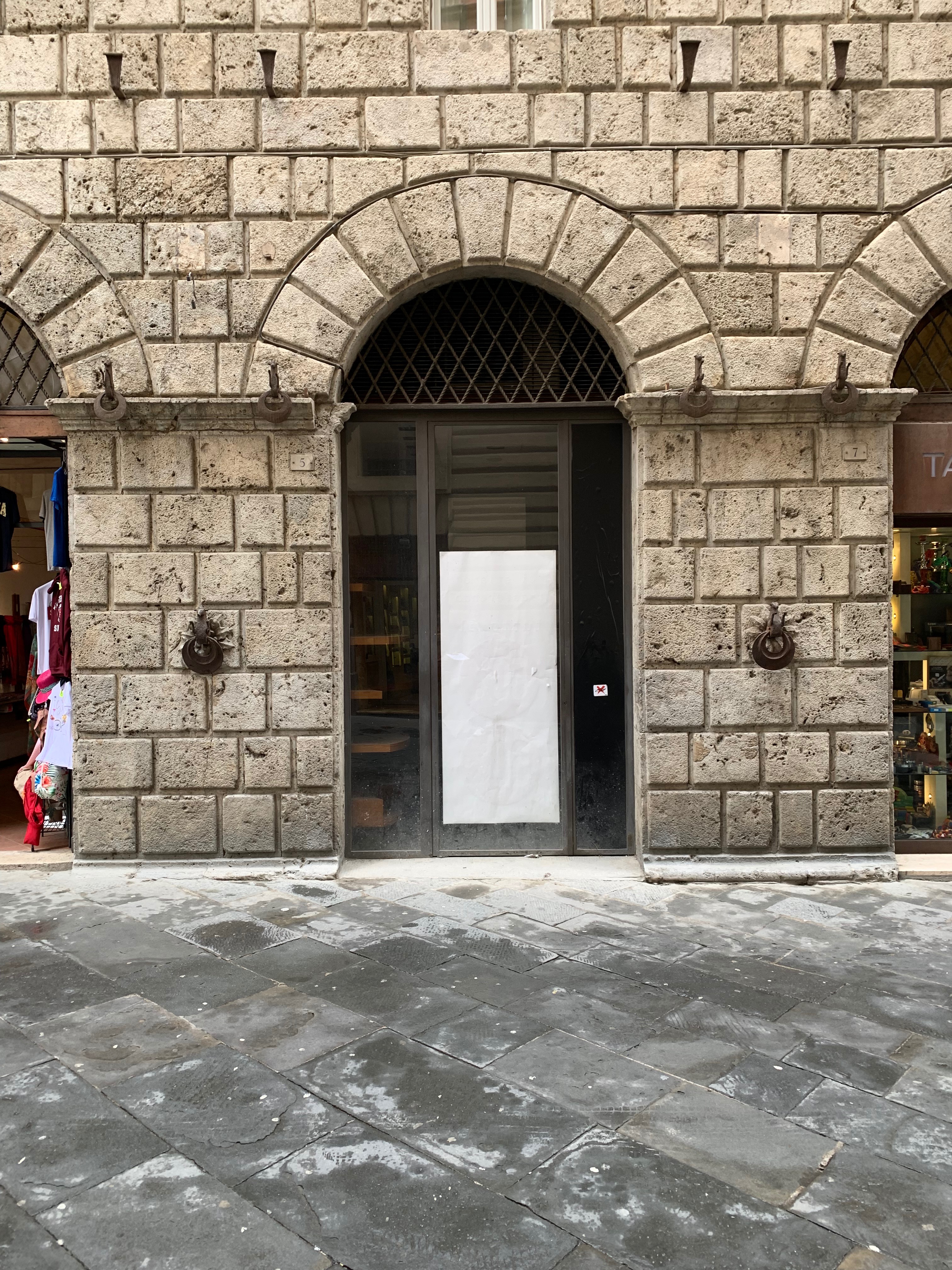 Unità immobiliare a destinazione commerciale situata al piano terra di un edificio di carattere storico-artistico denominato “Palazzo Piccolomini”. La parte più antica, di cui fa parte l'unità immobiliare in esame, è stata costruita su progetto del Rossellino ed era anticamente la dimora della celebre famiglia senese dei Piccolomini. Il fondo commerciale risulta composto da un vano al piano terreno di circa 32 mq, ed un magazzino con servizio igienico al piano primo di circa 29 mq. Nel locale al piano terreno, con accesso da via Rinaldini è stata ricavata una vetrina. Identificativi catastali: C.F. del Comune di Siena Foglio 34, particella 11, subalterno 3.