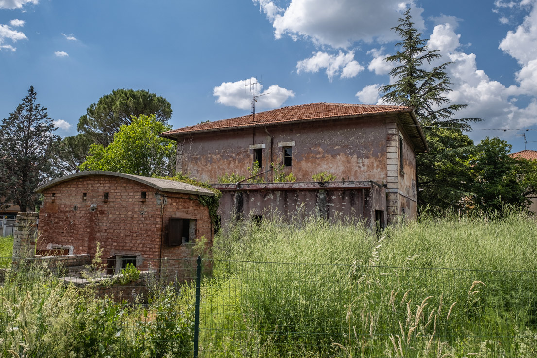Compendio costituito da un fabbricato diviso in 2 unità immobiliari destinate ad abitazione, con annessi garages, stalletto e relativa area pertinenziale recintata. La costruzione risale agli anni ’30 del secolo scorso e presenta le caratteristiche tipologiche della casa cantoniera bifamiliare. Il complesso presenta potenzialità edificatoria residua, compatibile con il vincolo d’interesse culturale a cui è soggetto. Identificativi catastali: CT del comune di Foligno Fg 106 part. 1925 e CF del comune di Foligno Fg 106 part. 1925 subb 4, 5, 6, 7 e, 8 (graffato con sub 5).