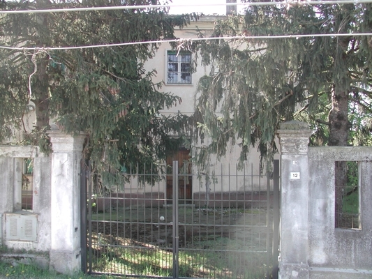 Complesso alloggiativo costituito da due corpi di fabbrica, uno dei quali adibito a residenziale e l'altro a box auto e locali deposito. L'edificio residenziale, a base quadrata, si sviluppa su 2 piani fuori terra che ospitano 2 unità abitative, unitamente ad un piano interrato adibito a cantine (n. 2 locali cantina). Il secondo corpo di fabbrica, a base rettangolare, si sviluppa su un unico piano fuori terra ed è costituito da numero 3 box auto e numero 2 locali deposito. L'intero complesso alloggiativo è dotato di una vasta area esterna di pertinenza esclusiva completamente recintata. Risultano di pertinenza 4 locali deposito, 3 box auto. Identificativi catastali Foglio 20, Part.162.