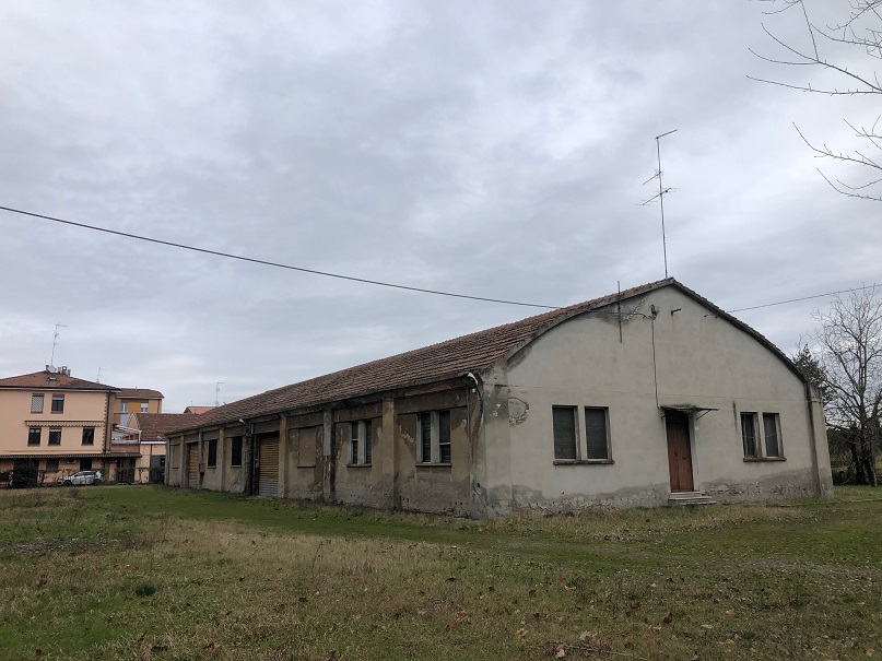 MAGAZZINO FORAGGI S. CATERINA. MODENA cap - 41122, STRADA SANTA CATERINA SNC. Nella zona semicentrale ad Est del centro storico, quartiere Crocetta, costituito da un edificio su un livello con copertura ad arco rialzato con tegole marsigliesi, destinato a deposito per il fieno, fino ad oggi in uso governativo all'Accademia Militare (di interesse culturale con Decreto della Soprintendenza Regionale per i Beni e le Attività Culturali dell'Emilia Romagna n. 03/011 in data 19/03/2003), ben collegata dai mezzi pubblici, raggiungibile dalla stazione ferroviaria di Modena e distante circa 11 km dal casello Modena Sud dell’autostrada A1. Identificativi catastali: cat. D8 Fg. 112, Part. 77, Sub. 1. Sup. scoperta MQ 4.511 sup. catastale MQ 832.