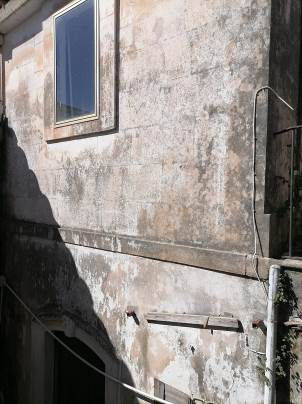 Fabbricato ant. al 1942, costituito da piccolo ingresso, due ampi vani comunicanti con un disimpegno da cui si accede al cortile esterno. Dal cortile si accede al servizio igienico e, tramite una scala, al piano primo terrazzo e un altro vano. Stato di degrado, costi di ripristino circa € 18.288,36. Censito in catasto come “sala giochi” con relativa agibilità. Un vano abusivo al primo piano delle seguenti dimensioni mq. 2,70 per 3,30. E’ ammessa la sola ristrutturazione edilizia con prospetto vincolato, caratterizzato da elementi pietra. Validità art. 48, comma 5 del D. Lgs. 159/2011. Un vano sito al primo piano al livello del terrazzo non rappresentato dalla planimetria catastale di 10,00 m2. Identificativi [N.C.E.U.] Fg. 17, part. 7271 (ex fg. 20, part. 238), cat. C/1   SUP. MQ (ARR.) 82