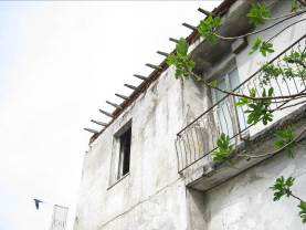 L’edificio in totale abbandono. Al piano terra una unità immobiliare con accesso dall’ingresso comune con le due unità abitative, composta da quattro vani per ufficio, due servizi igienici e corridoio suddiviso in due distinte porzioni.  Al piano terreno nella parte ovest un unico locale a pianta rettangolare utilizzata come rimessa. Il piano primo, cui si perviene mediante ingresso e scala interna a comune, è costituito da due unità immobiliari ad uso residenziale disabitate da 10 anni. L’appartamento sul lato est, dotato anche di accesso autonomo dallo stradello retrostante, si compone di tre vani, cucina, corridoio e servizio igienico. L’appartamento sul lato ovest si compone di tre vani, cucina, servizio igienico e corridoio, e piccolo ripostiglio sottoscala situato al piano terreno.