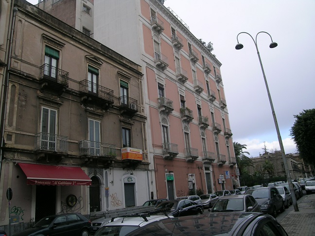 Immobile destinato ad uffici, parte di fabbricato di sei piani, con struttura verticale in muratura portante e copertura a terrazzo. Facciate con intonaco e decorate con cornici e fregi in pietra e gesso, gli infissi e il portone d’ingresso sono in legno. I fronti prospicienti Piazza Giovanni Verga, con piano terra costituito da attività commerciali e quattro piani con destinazioni prevalenti uffici oltre il piano attico. Le unità immobiliari sono al quarto piano, collegate tra di loro da un’apertura interna. L’immobile esternamente in buono stato, all’interno in condizioni mediocri. In corso gli adempimenti per l’accertamento presso la Soprintendenza ai BB.CC.AA. di Catania della verifica di dichiarazione di interesse culturale (V.I.C.). Sup. Mq (Arr) 302. Lotto Libero, Piena Proprietà.