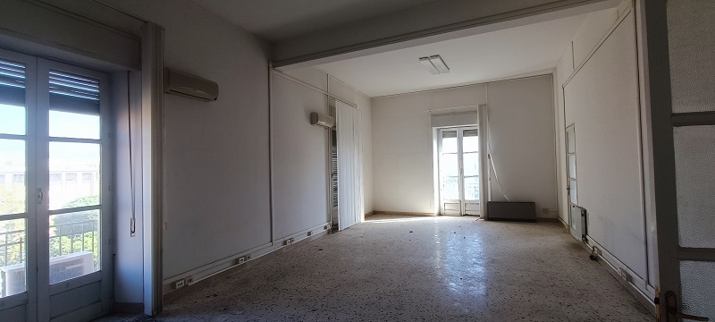 Immobile destinato ad uffici, parte di fabbricato di sei piani, con struttura verticale in muratura portante e copertura a terrazzo. Facciate con intonaco e decorate con cornici e fregi in pietra e gesso, gli infissi e il portone d’ingresso sono in legno. I fronti prospicienti Piazza Giovanni Verga, con piano terra costituito da attività commerciali e quattro piani con destinazioni prevalenti uffici oltre il piano attico. Le unità immobiliari sono al quarto piano, collegate tra di loro da un’apertura interna. L’immobile esternamente in buono stato, all’interno in condizioni mediocri. In corso gli adempimenti per l’accertamento presso la Soprintendenza ai BB.CC.AA. di Catania della verifica di dichiarazione di interesse culturale (V.I.C.). Sup. Mq (Arr) 302. Lotto Libero, Piena Proprietà.