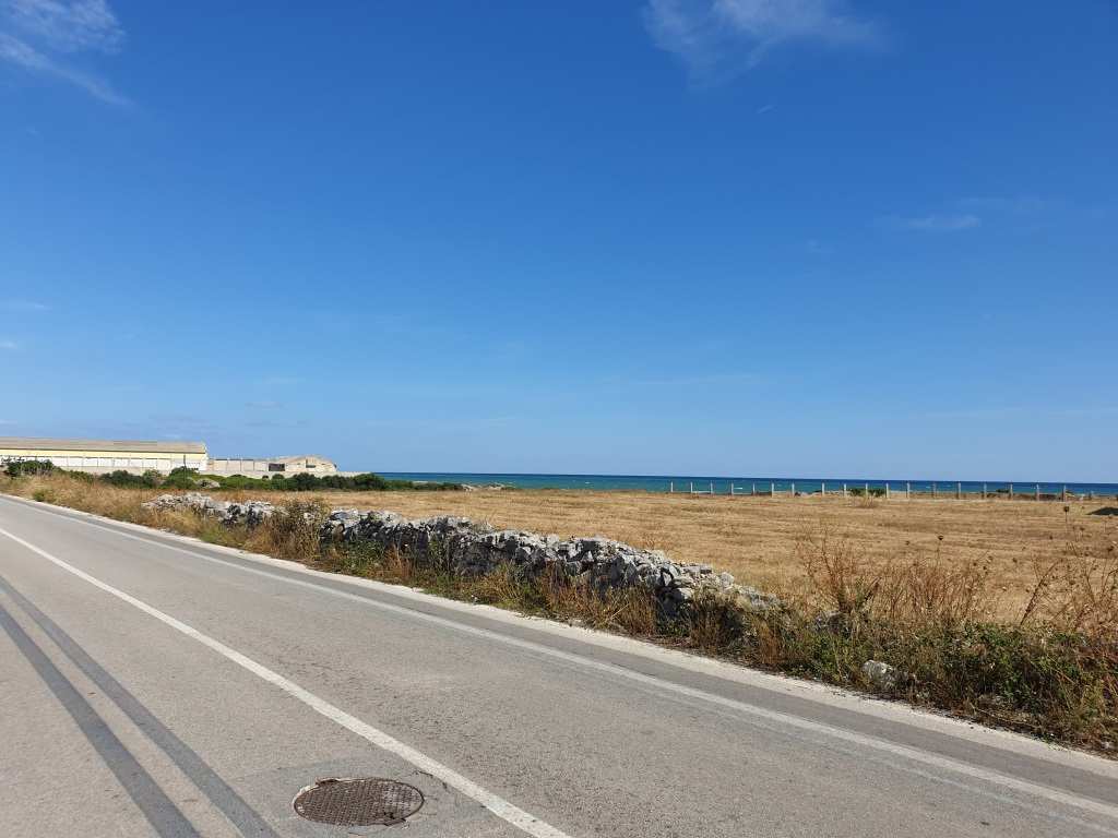 Il terreno, di natura agricola è ubicato in zona caratterizzata da terreni la cui destinazione ordinaria è quella seminativi, sul lato mare SS 16, e di uliveto verso l'interno. A confine con i terreni in esame vi sono capannoni artigianali, mentre a poche centinaia di metri è ubicato un complesso residenziale destinato a villini. I suoli. censiti al catasto terreni con la qualità seminativo, sono attualmente incolti; nel loro insieme hanno forma irregolare, assomigliante ad una L, e giacitura pianeggiante. I terreni sono cintati in parte da muro a secco. Dalla mappa catastale risulta rappresentata sulla particella 29 una costruzione di forma conica in pietra a secco, tipica delle zone rurali pugliesi, non più esistenti in loco