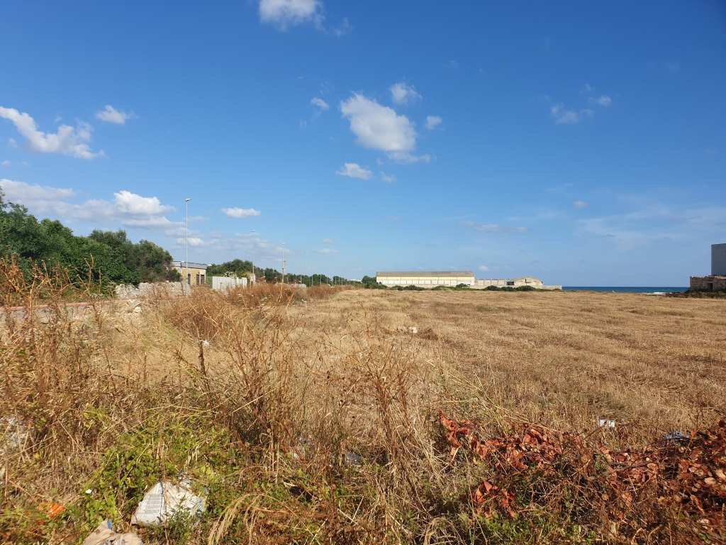 Il terreno, di natura agricola è ubicato in zona caratterizzata da terreni la cui destinazione ordinaria è quella seminativi, sul lato mare SS 16, e di uliveto verso l'interno. A confine con i terreni in esame vi sono capannoni artigianali, mentre a poche centinaia di metri è ubicato un complesso residenziale destinato a villini. I suoli. censiti al catasto terreni con la qualità seminativo, sono attualmente incolti; nel loro insieme hanno forma irregolare, assomigliante ad una L, e giacitura pianeggiante. I terreni sono cintati in parte da muro a secco. Dalla mappa catastale risulta rappresentata sulla particella 29 una costruzione di forma conica in pietra a secco, tipica delle zone rurali pugliesi, non più esistenti in loco