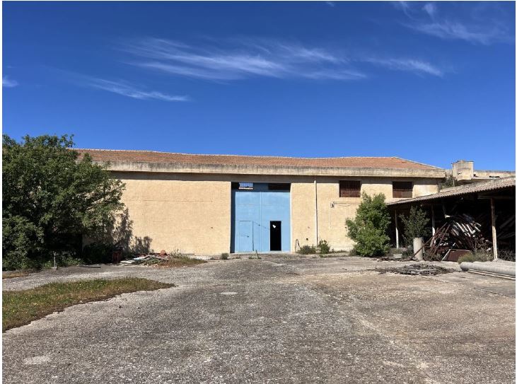 Magazzino di circa 400 m2. L’immobile occupa una superficie di circa 400 mq ed insiste su un appezzamento di terreno di circa 1210 mq;la struttura è realizzata in acciaio ed è tamponata con conci di tufo con finitura in malta di cemento, sabbia e grassello; il tetto è realizzato con architravi e traversi in legno che sorreggono una copertura in legno lamellare su cui a sua volta poggiano tegole in laterizio. La pavimentazione è realizzata in cemento battuto. Id. cat. [N.C.E.U.] foglio 64, particella 560 e 559. Sup. (arr) 400 mq + 800 mq piazzale